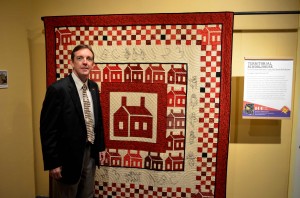 Ken Bennett with Prescott's Heritage Quilt And Study Group of the Sharlot Hall Museum's quilt, "Territorial Schoolhouse."